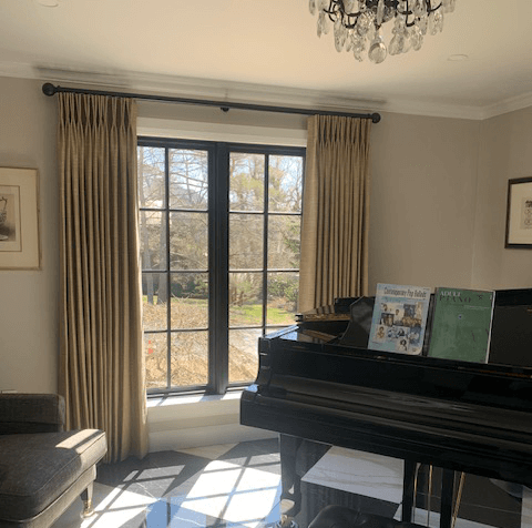 Living room with piano, elegant draperies, and a couch.